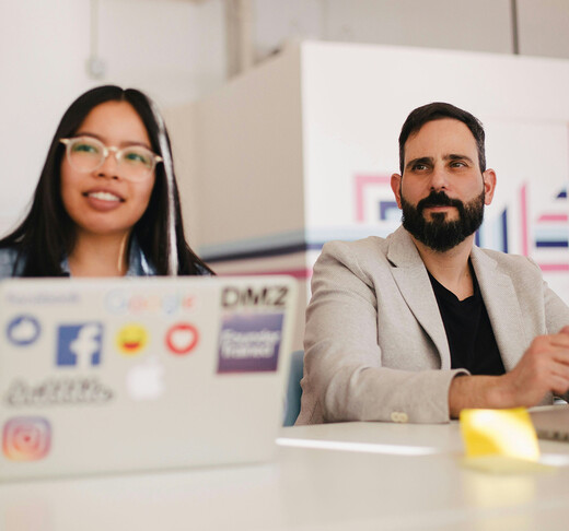 two teachers seated at a table with an open laptop in front of them